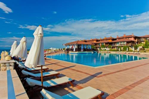 a pool at a resort with lounge chairs and umbrellas at Sozopolis Holiday Village in Sozopol
