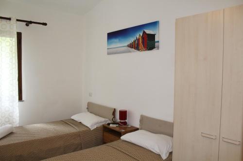 Habitación con 2 camas y una foto en la pared. en Affittacamere la Medusa en Porto Pino