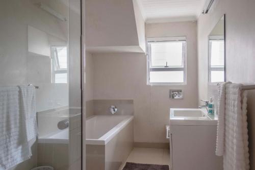 a white bathroom with a tub and a sink at Hilton Cove Beach House in Melkbosstrand