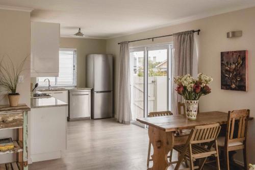 a kitchen with a table with flowers on it at Hilton Cove Beach House in Melkbosstrand