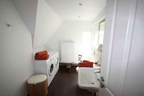 ein weißes Bad mit einem Waschbecken und einem WC in der Unterkunft Hus Wattkieker 7b in Husum