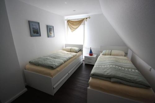 a bedroom with two beds and a window at Hus Wattkieker 7b in Husum