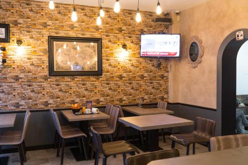 a restaurant with wooden tables and chairs and a brick wall at Hôtel des Beaux Arts in Chambéry