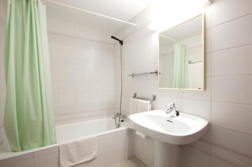 ein weißes Badezimmer mit einem Waschbecken und einem Spiegel in der Unterkunft Apartamentos Playa Es Cana in Es Cana