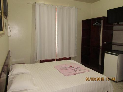 Pousada Beija Flor في Cambuci: غرفة نوم بسرير ابيض مع نافذة