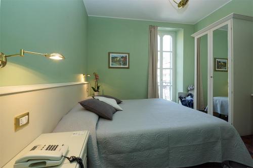 Un dormitorio con una cama y un teléfono en una mesa. en Hotel Splendid Mare en Laigueglia