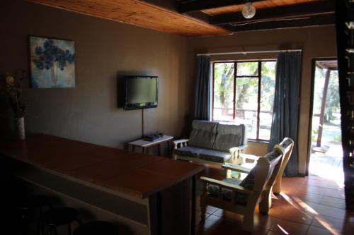 a living room with a table and chairs and a television at Little Rock Resort in Ladybrand