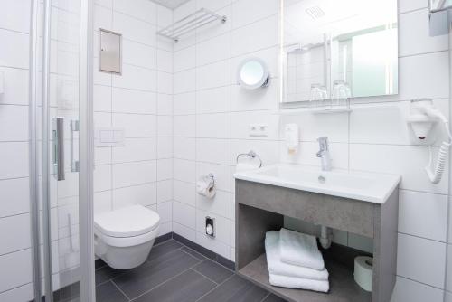 a white toilet sitting next to a white sink at Stadthotel Freiburg Kolping Hotels & Resorts in Freiburg im Breisgau
