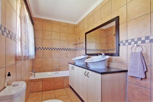 a bathroom with a sink and a toilet and a mirror at Monateng Safari Lodge in Wallmannstal