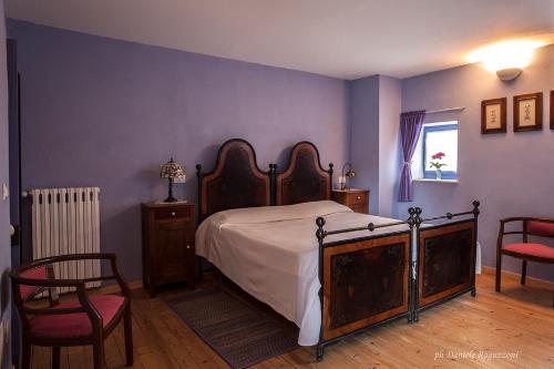 a bedroom with a bed and two chairs and a window at La Corte di Alzo in Pella