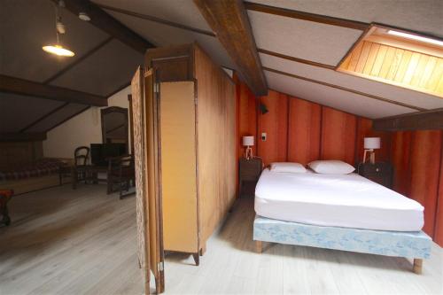 モルジヌにあるTriolet 2の大きなベッドと木製の壁が備わるベッドルーム1室が備わります。