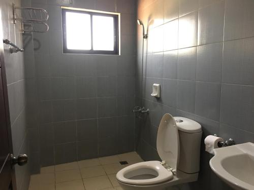 a bathroom with a toilet and a sink and a window at South Prince Residences and Inn in Davao City