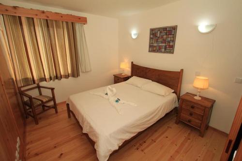 a bedroom with a bed and a chair and a window at Casa Branca da Vaquinha in Angra do Heroísmo