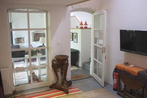 a living room with a tv and a room with a door at Bake House Cottage in Shepton Mallet
