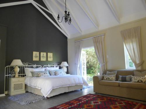 een slaapkamer met een wit bed en een bank bij The Plantation in Port Elizabeth