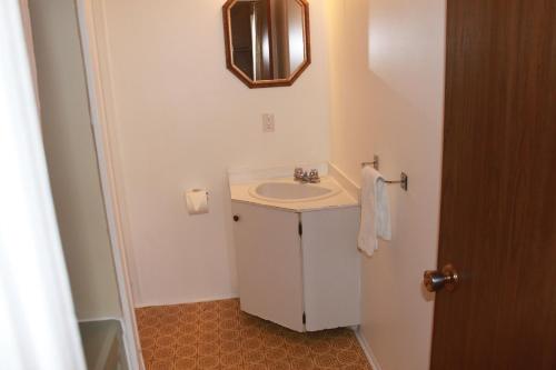 a white bathroom with a sink and a mirror at Motel Boisé in Blainville