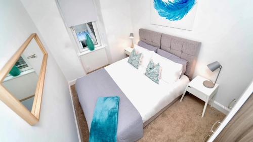 a small bedroom with a white bed and a mirror at Snug - Tùr Sealladh Apartment in Helensburgh