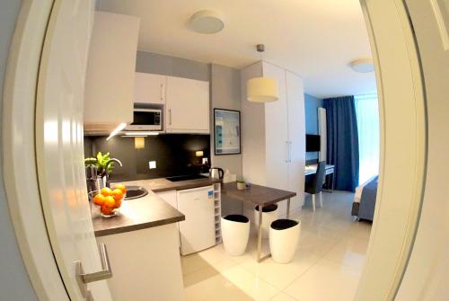 kuchnia z białymi szafkami i stołem z owocami w obiekcie JessApart – Ochota Apartments w Warszawie