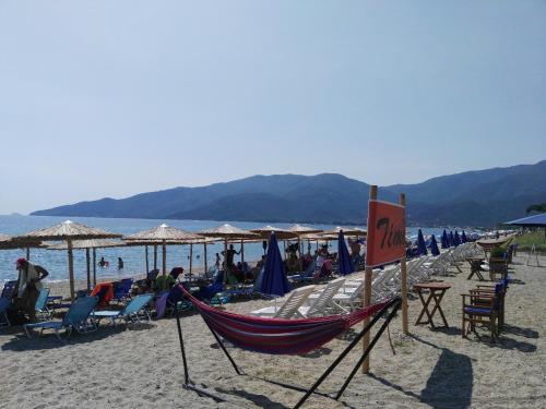 a beach with chairs and umbrellas and a hammock at Sunny summer time in Nea Vrasna