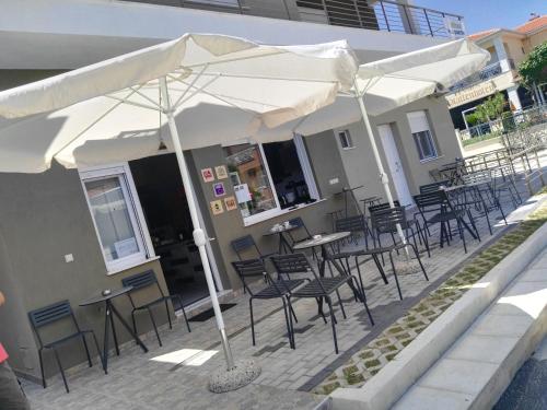 a patio with tables and chairs under an umbrella at Sunny summer time in Nea Vrasna