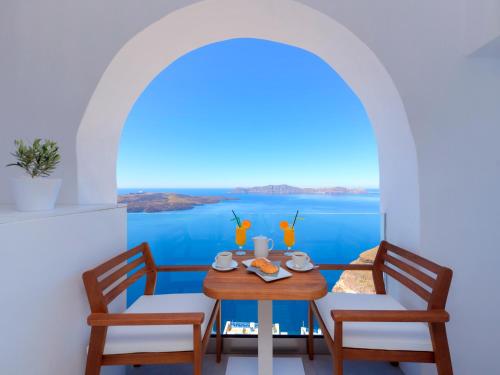 a table and chairs with a view of the water at Iriana Suites in Fira