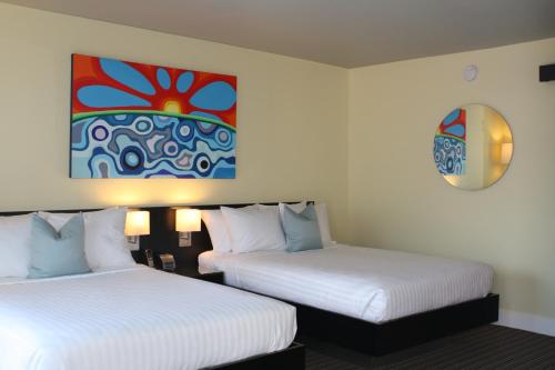 a hotel room with two beds and a painting on the wall at Hotel Current in Long Beach