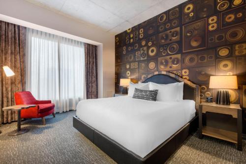 a hotel room with a bed and a red chair at Cambria Hotel Nashville Downtown in Nashville