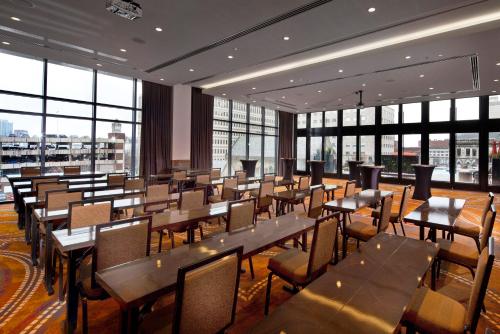 a restaurant with tables and chairs and large windows at Cambria Hotel Nashville Downtown in Nashville