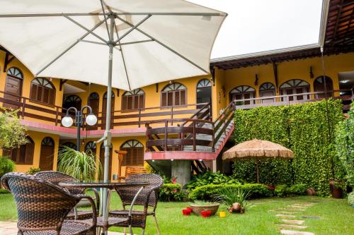 a table with an umbrella in front of a building at Pousada da Terra in Natal