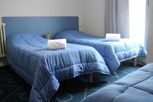 ルルドにあるLe Petit Majesticのブルーシーツ付きの客室内のベッド2台