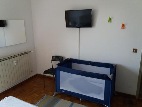 a room with a blue crib and a tv on a wall at Guido's Apartment Villa Romana in Desenzano del Garda