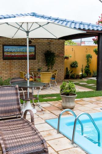 a patio with an umbrella and a table and chairs at Pousada da Terra in Natal