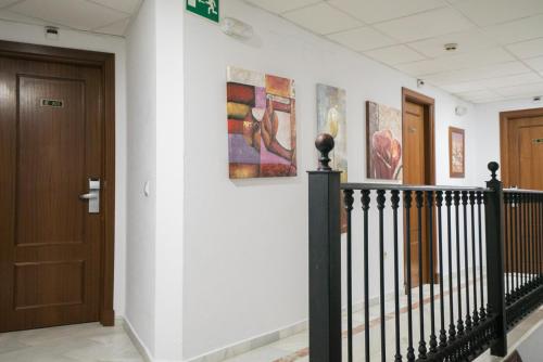 a hallway with a door and paintings on the wall at Hotel Pozo del Duque II in Zahara de los Atunes