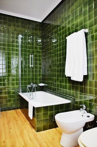 a green tiled bathroom with a tub and a toilet at Hospedium Hotel La Marina Costa da Morte in Cee