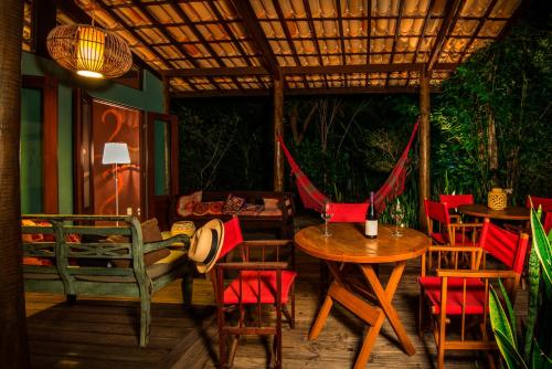 a patio with tables and chairs and a hammock at Casa Morada dos Pássaros - 3 suítes in Imbassai