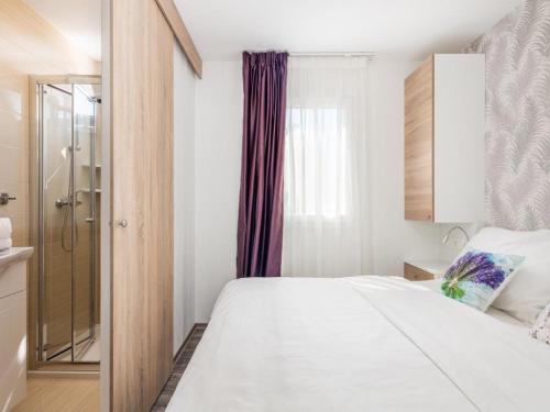 een slaapkamer met een wit bed en een douche bij Brugor Mobil Homes Lavanda in Orebić