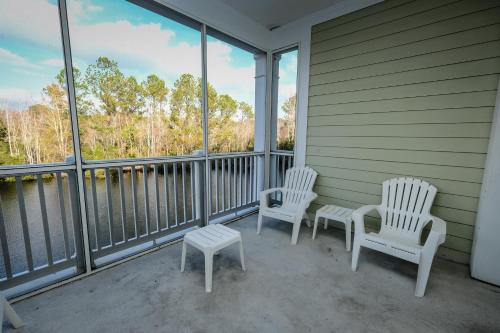 two chairs and a table on a porch with windows at Litchfield Beach & Golf Resort in Pawleys Island