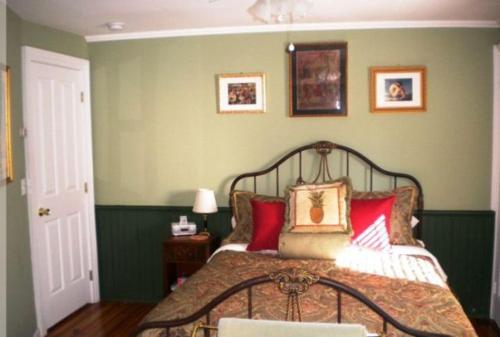 a bedroom with a bed with red pillows at The Stirling House Waterfront Inn Greenport in Greenport