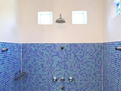 łazienka wyłożona niebieskimi kafelkami z 2 oknami na ścianie w obiekcie Cortijo El Pozuelo w mieście Tarifa