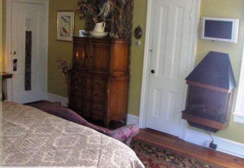 a bedroom with a bed and a dresser and a tv at The Stirling House Waterfront Inn Greenport in Greenport