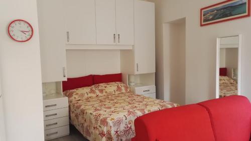 a bedroom with a bed and a red couch at Appartamento Madda in La Maddalena