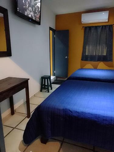 a bedroom with a blue bed with a desk and a window at Posada " El Jardín" in Xilitla