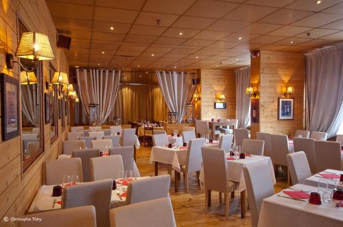 ラ・モンジーにあるHôtel-Restaurant La Mandiaのダイニングルーム(白いテーブル、椅子、テーブルサーチャー付)