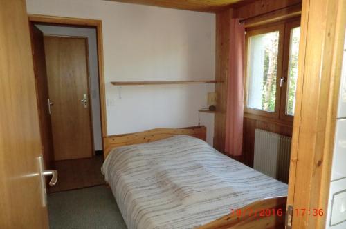 1 dormitorio con 1 cama en una habitación con ventana en Les passereaux, en Saint-Nicolas-de-Véroce
