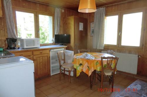 uma cozinha com mesa e cadeiras num quarto em Les passereaux em Saint-Nicolas-de-Véroce