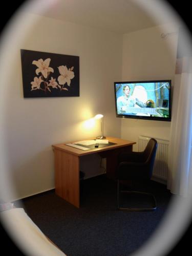 a room with a desk and a tv and a chair at Hotel zur Wasserburg in Kerpen