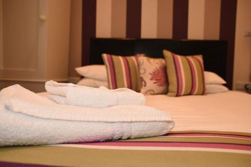 a pile of towels sitting on top of a bed at Harry's Hotel & Restaurant in Aberystwyth
