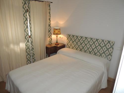a small bedroom with a white bed and a lamp at Apatamento Gargüera in Trujillo