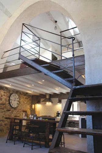 a spiral staircase in a room with a clock at Le Paillet Des Artistes in Saint-Vincent