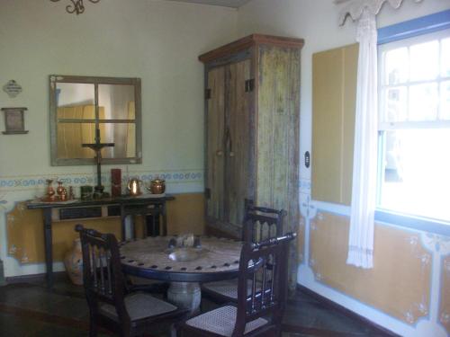 a dining room with a table and chairs and a mirror at Arraial Velho Pousada Tematica in Tiradentes